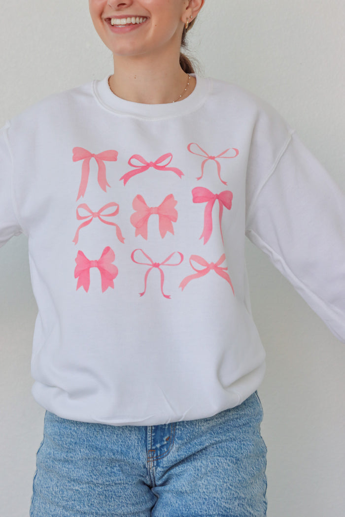 girl wearing white crewneck with pink bow screenprinted pattern