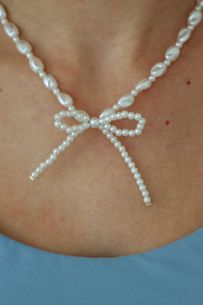 girl wearing pearl bow necklace