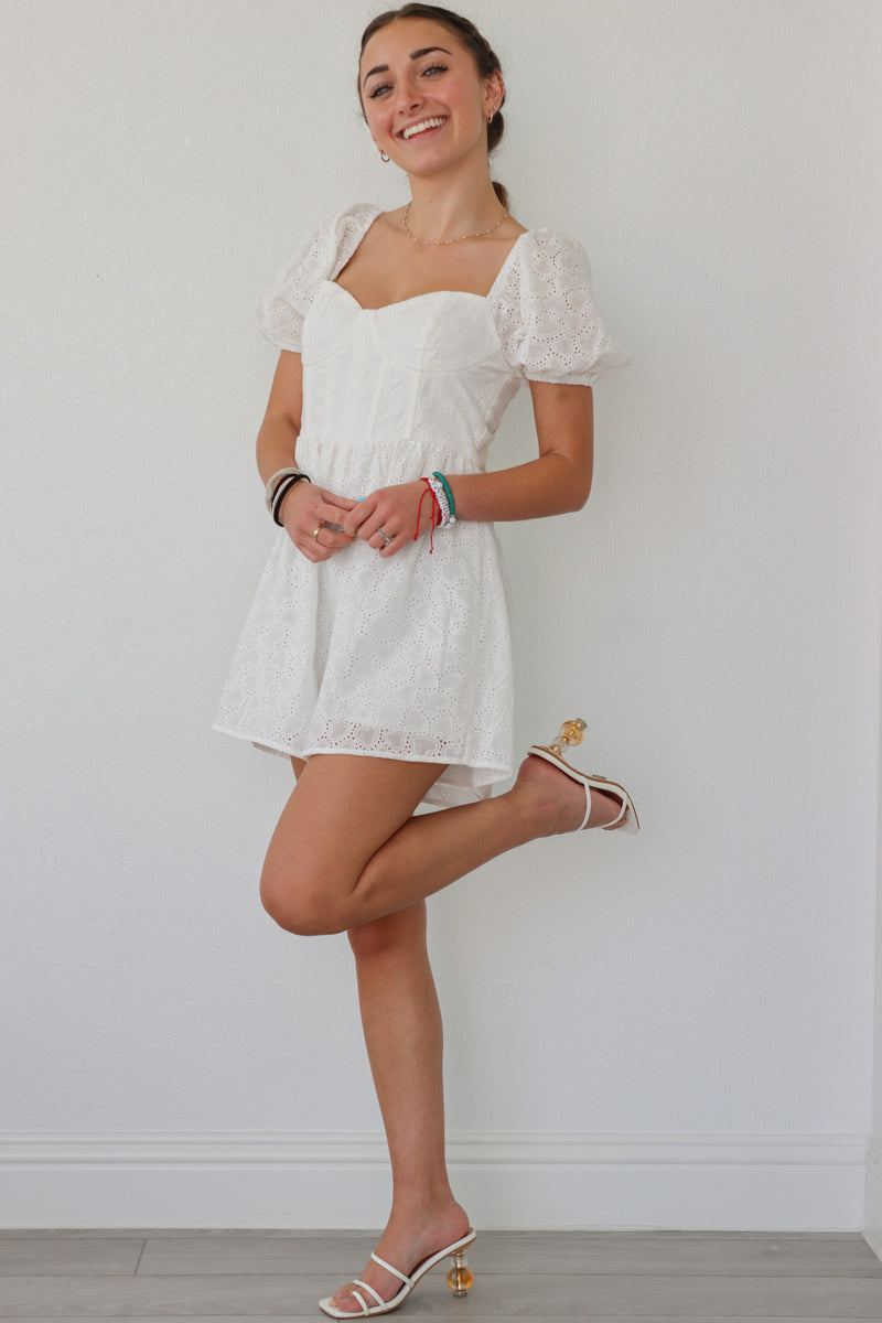 girl wearing white romper with puff sleeves and heart eyelet fabric