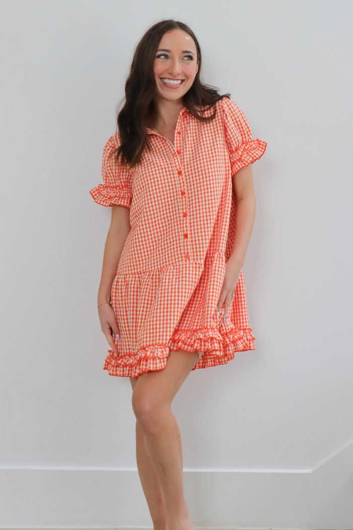 girl wearing orange gingham ruffled dress