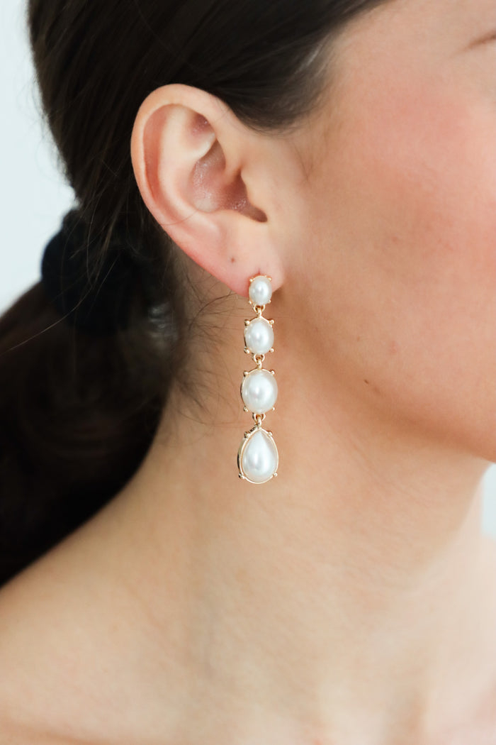 girl wearing gold and pearl drop earrings
