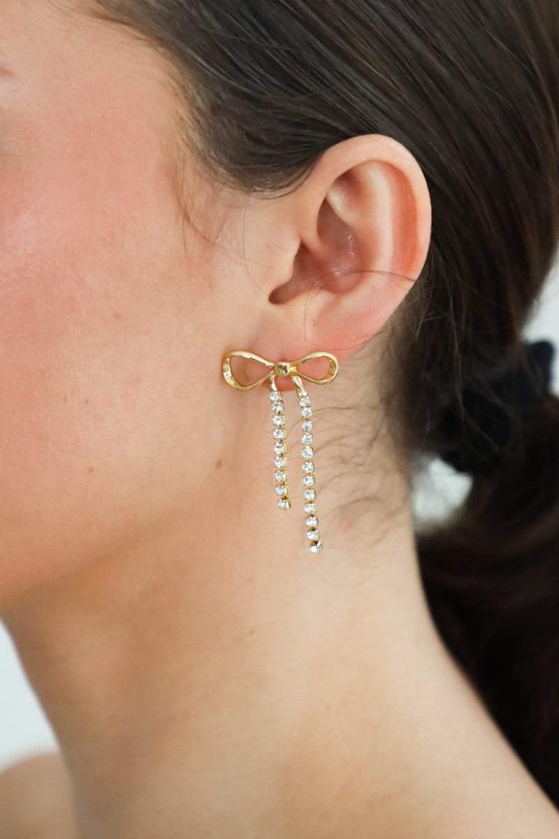 girl wearing gold rhinestone bow earrings