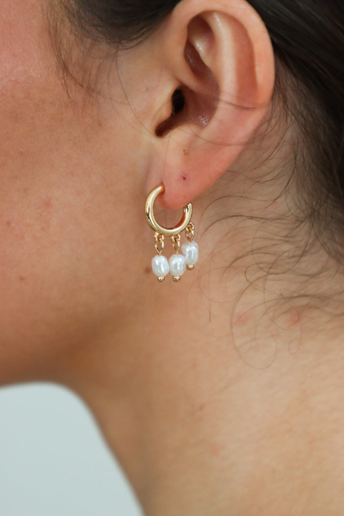 girl wearing gold and pearl hoop earrings