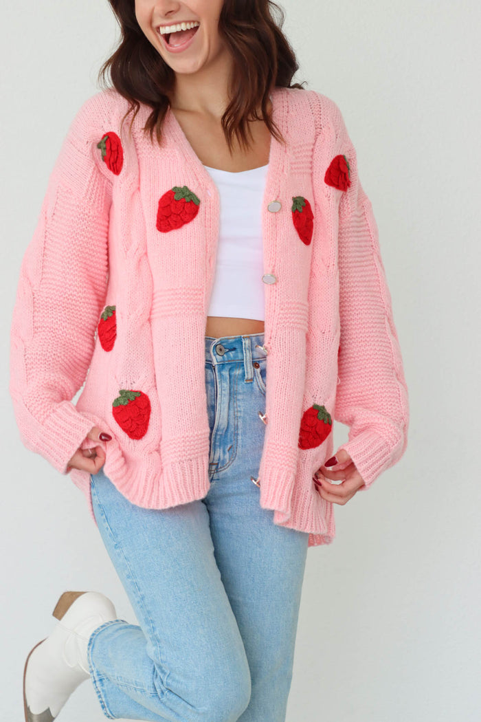 girl wearing pink knit cardigan sweater with red strawberry crochet detailing