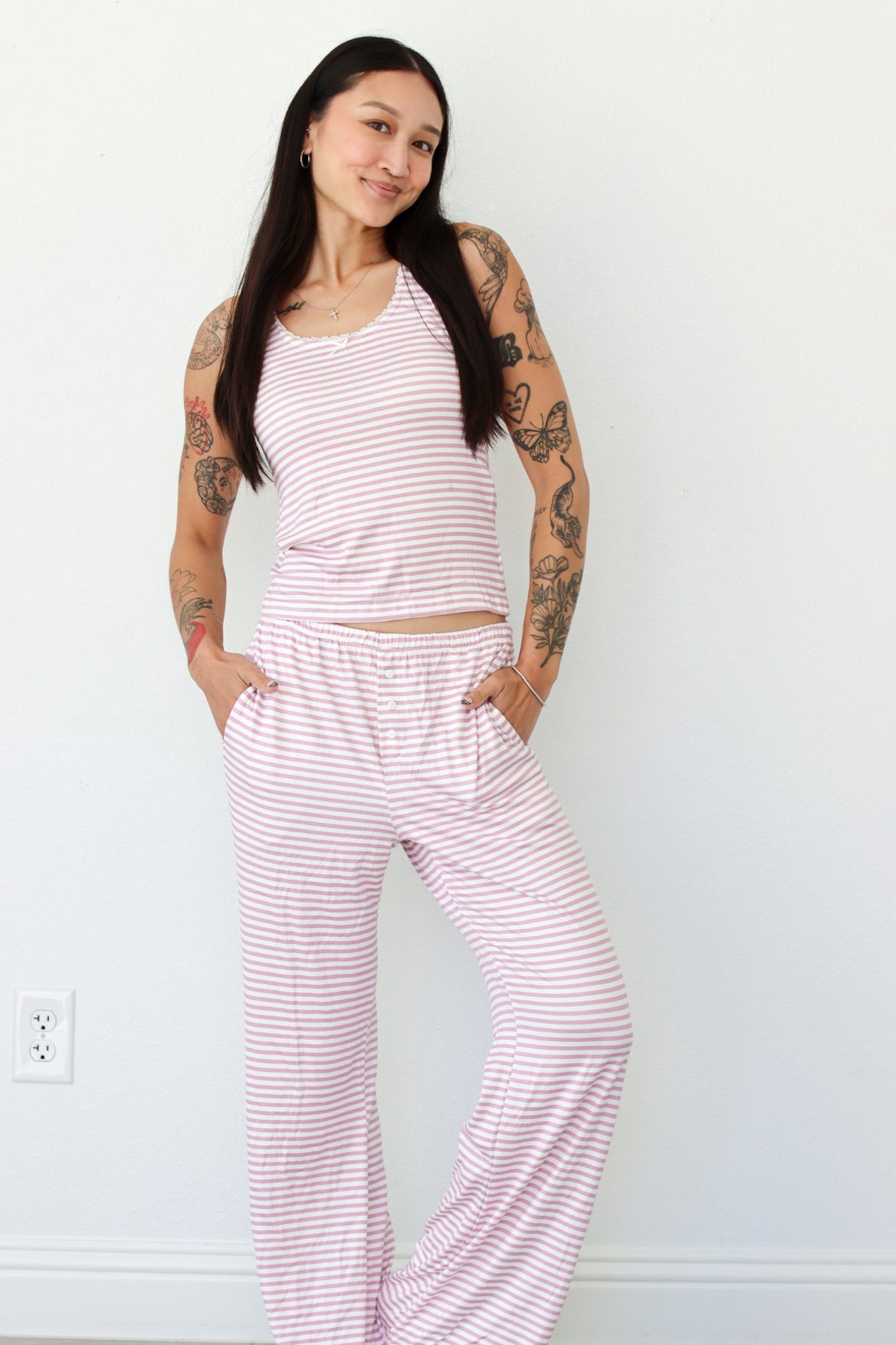 Woman wearing a pink striped tank and pant pajama set 