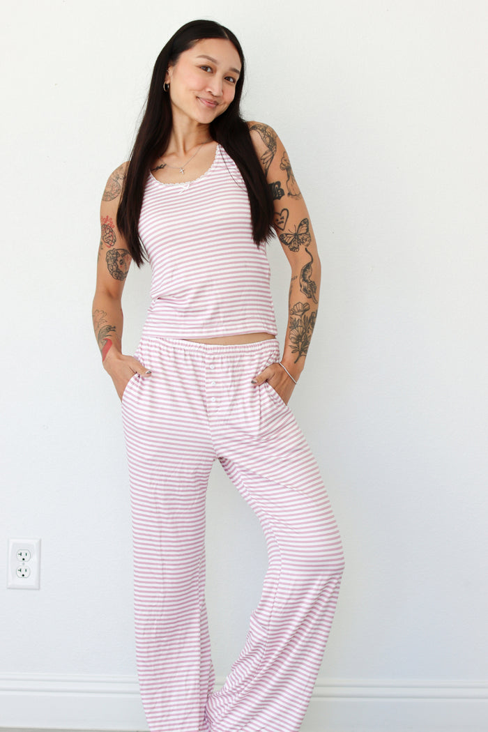 Woman wearing a pink striped tank and pant pajama set 