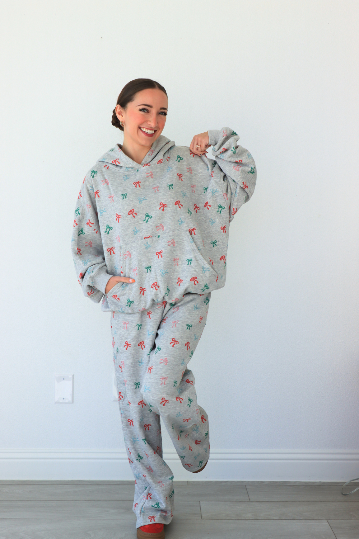 Person wearing a gray onesie with colorful patterns against a white wall.