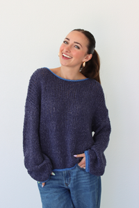 Woman wearing a dark blue sweater and jeans against a white background