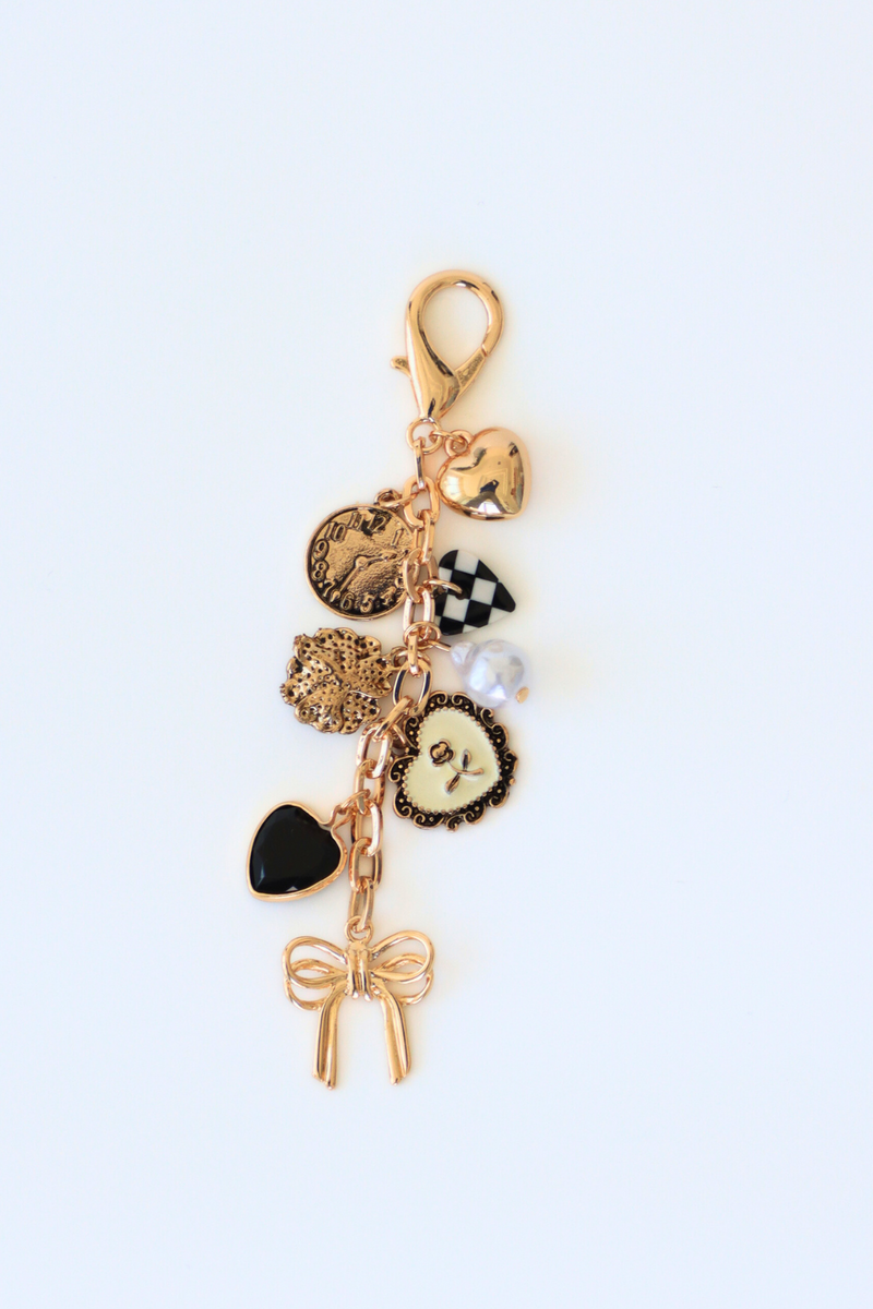 Gold charm keychain with various charms on a white background