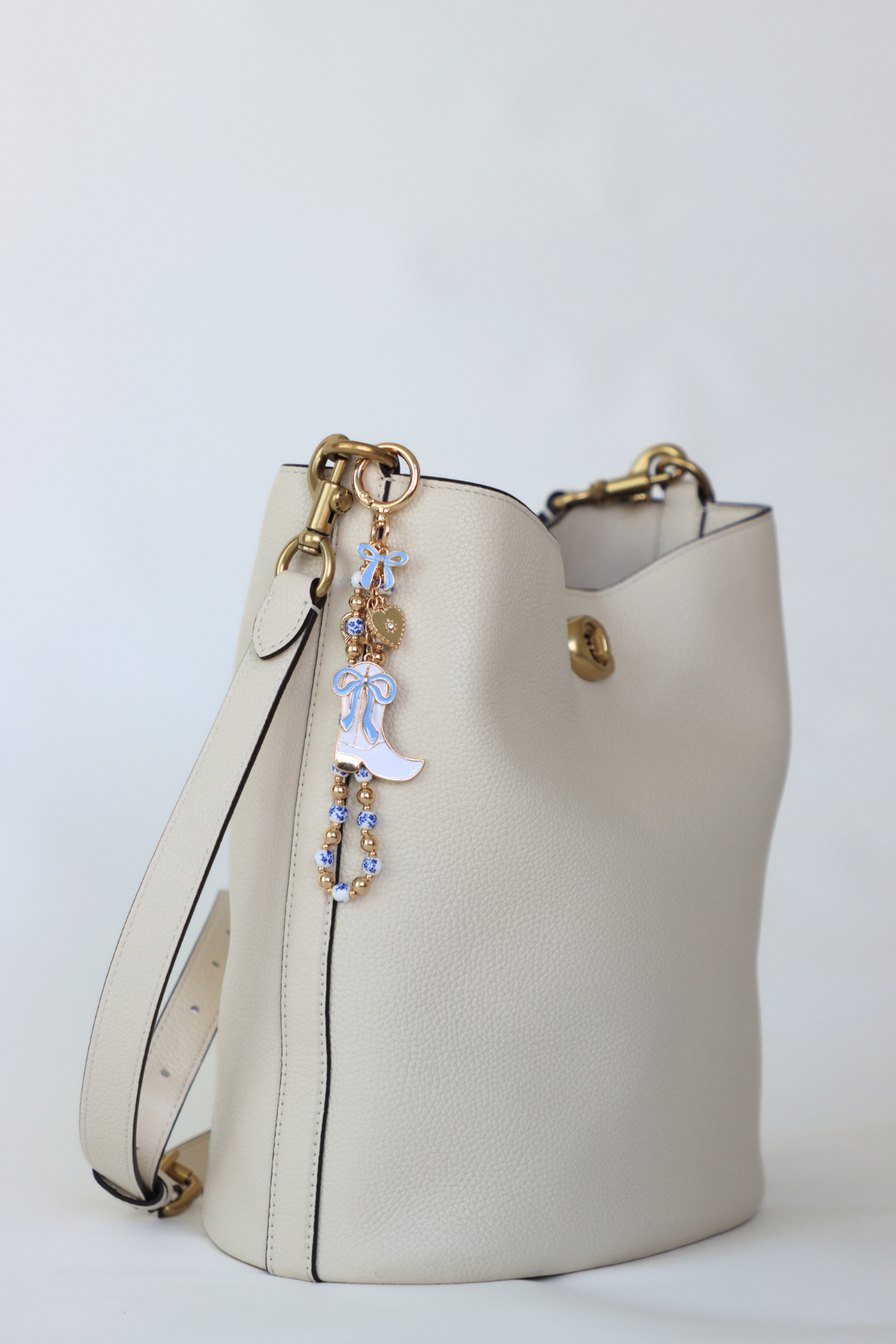 White handbag with decorative charm on a light gray background