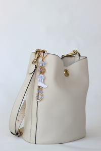 White handbag with decorative charm on a light gray background