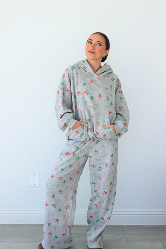 Person wearing a gray fleece onesie with colorful designs against a white wall.