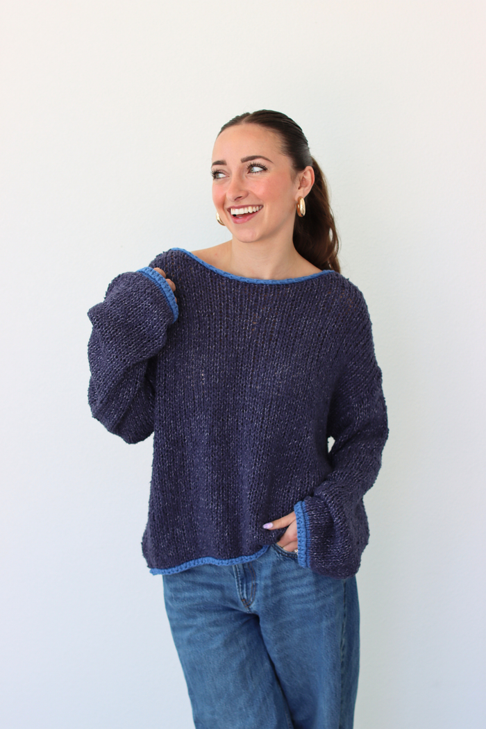 Woman wearing a dark blue sweater and jeans against a white background