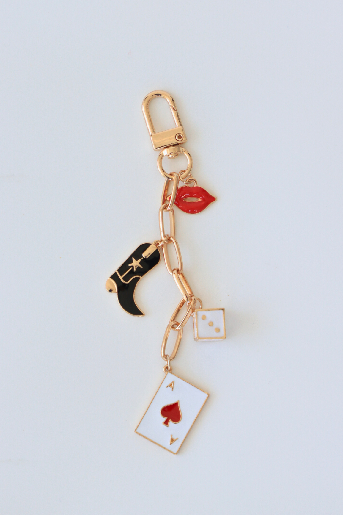 Keychain with various charms including a cowboy boot, card, and lip on a light gray background