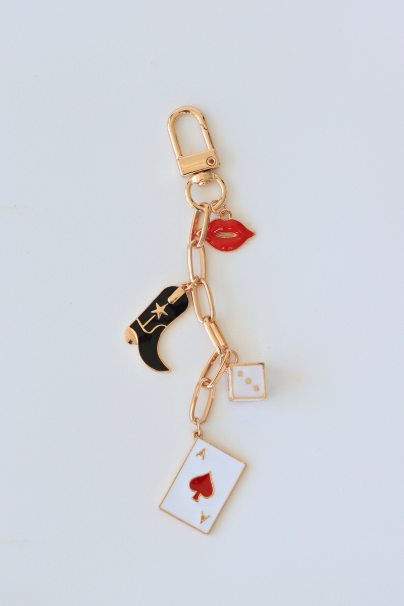 Keychain with various charms including a cowboy boot, card, and lip on a light gray background