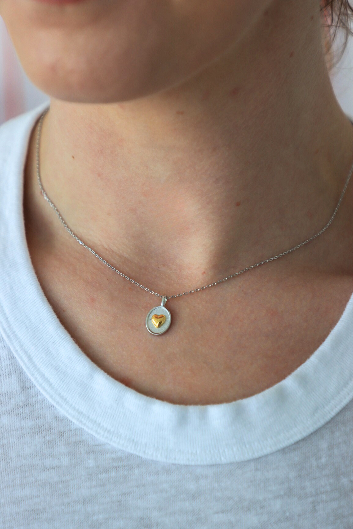 Necklace with a heart-shaped pendant worn by a person on a white background