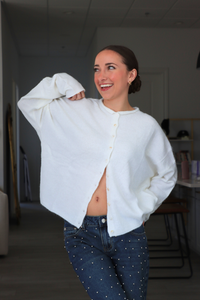 Woman wearing a white sweater and blue jeans indoors