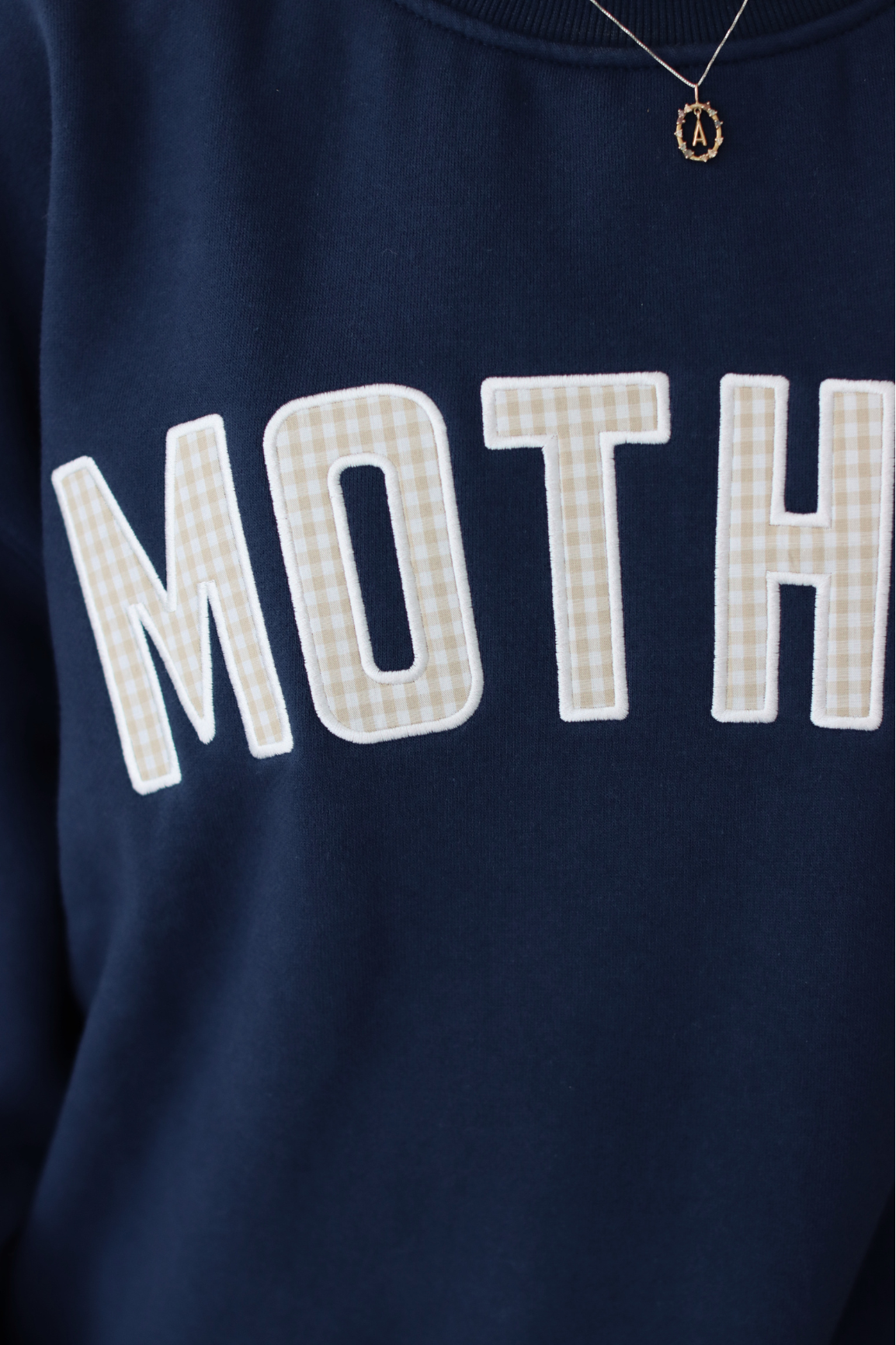 close up of gingham pattern on navy blue MOTHER sweatshirt 