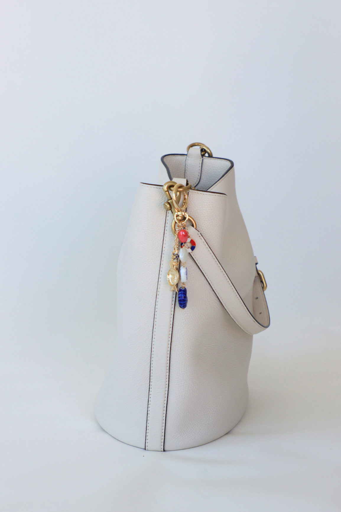 White handbag with colorful charms on a light gray background