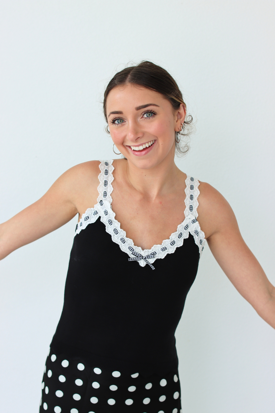 Woman wearing a black top and lace details on a light gray background
