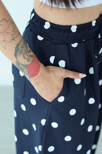 Navy blue pants with white polka dots worn by a person with tattoos on their arm.