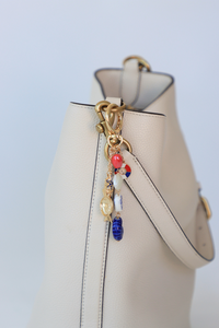 Beige handbag with a decorative charm on a light blue background