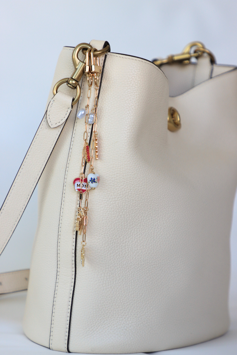 Beige handbag with decorative strap on a light gray background