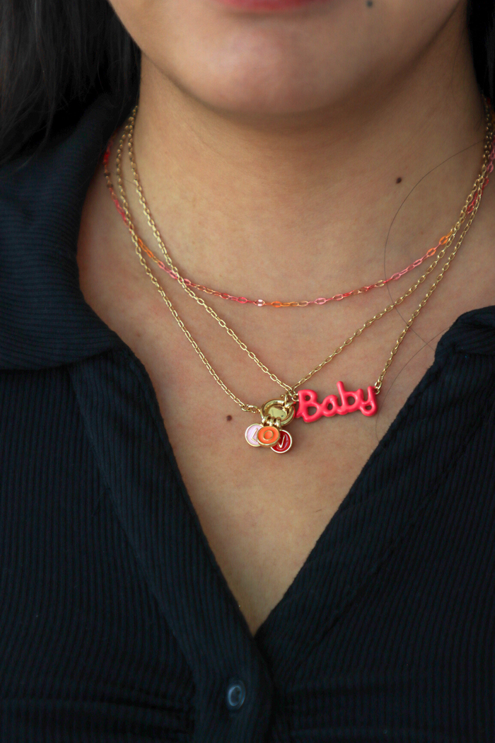 Necklace with 'Baby' pendant worn by a person against a dark background