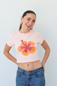 Woman wearing a pink t-shirt with a floral design against a light blue background