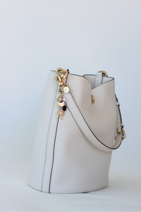 White bucket bag with gold charm on a light gray background