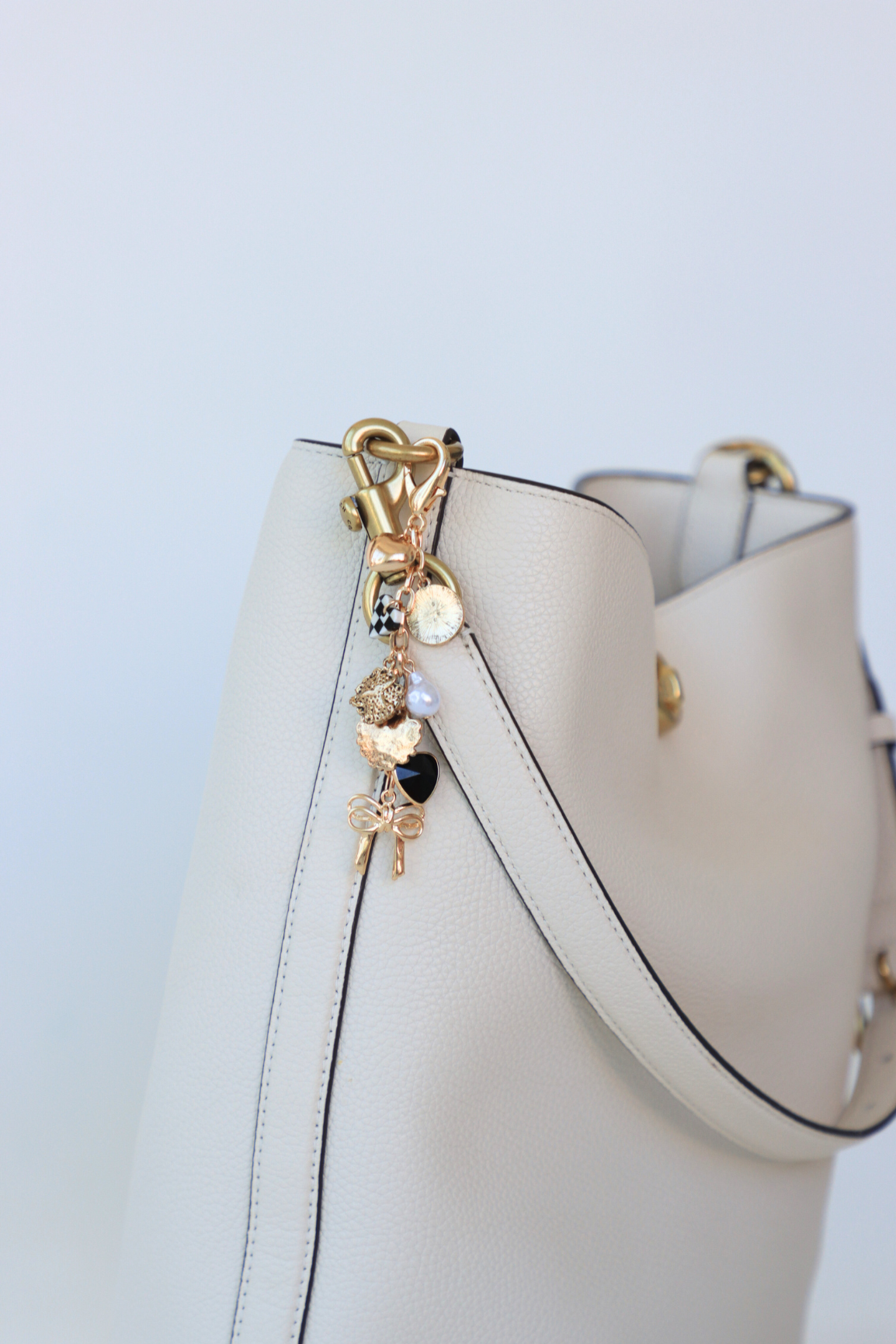White handbag with gold charm on a light blue background
