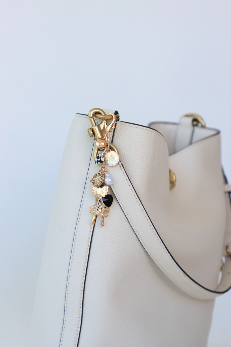 White handbag with gold charm on a light blue background