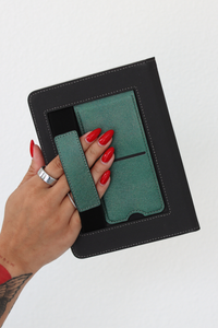 A hand with red manicured nails holds a kindle case with a green kickstand and hand strap against a plain white background.
