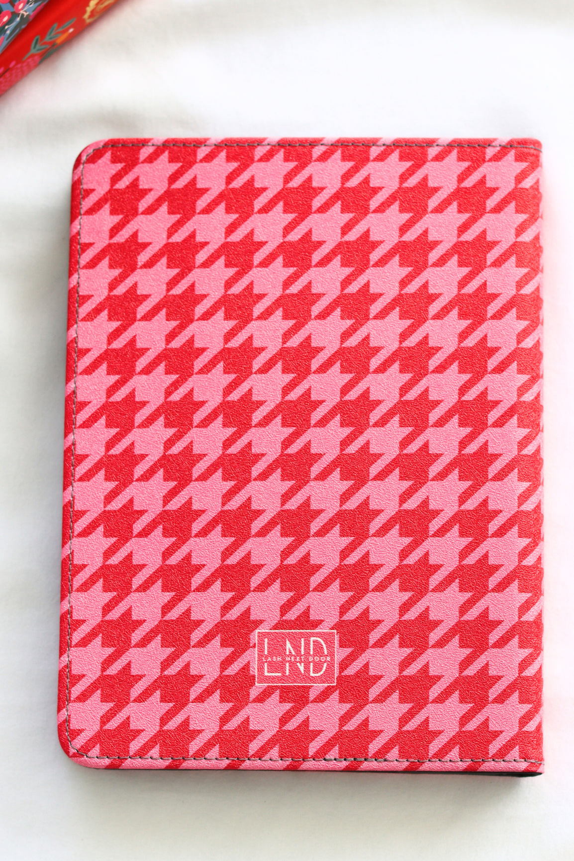 Pink and white houndstooth patterned kindle with 'LND' branding on a white background