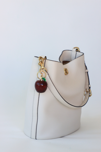 White handbag with a cherry charm on a white background