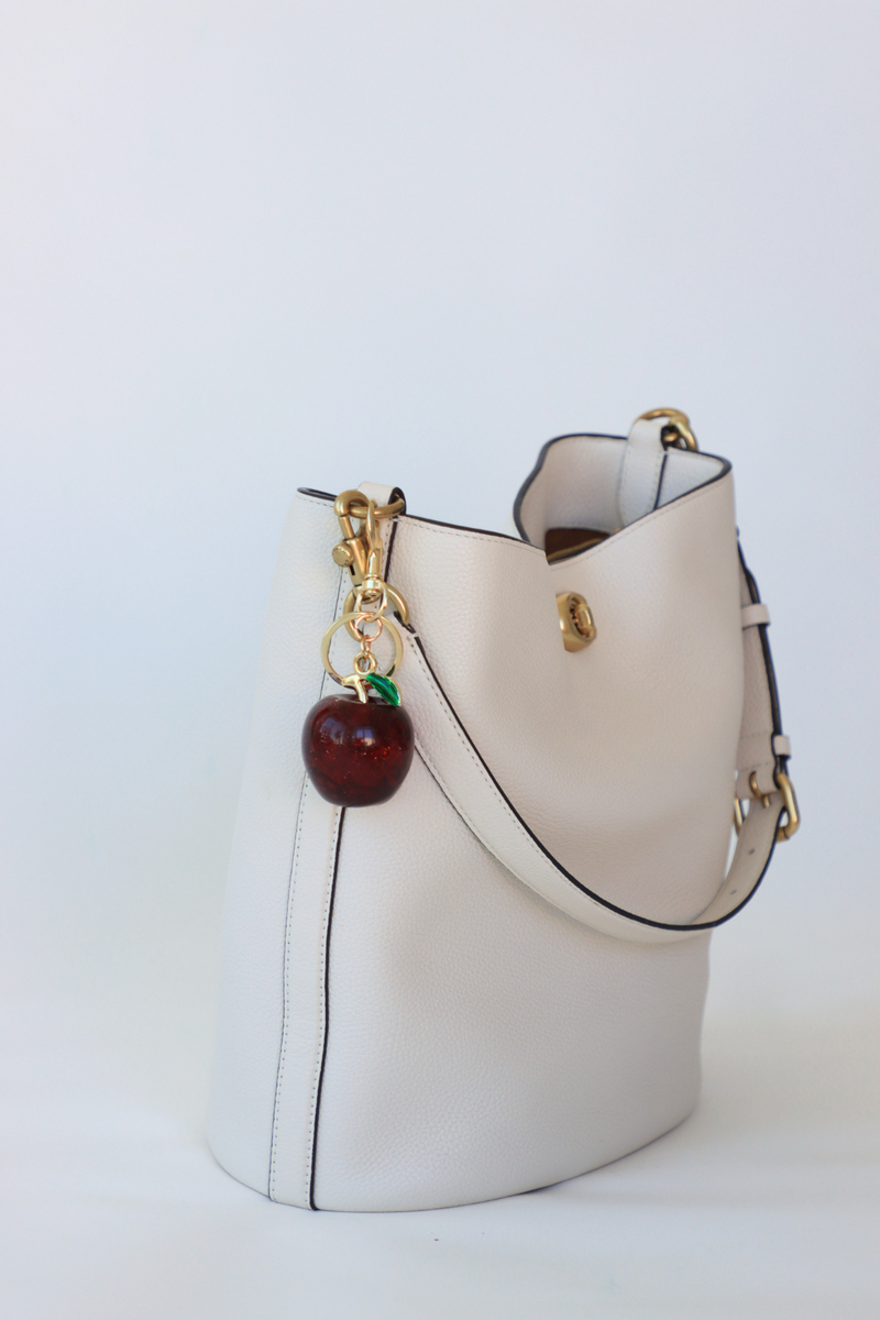 White handbag with a cherry charm on a white background