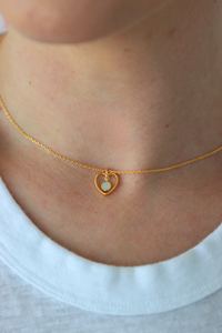 Gold necklace with a heart-shaped pendant worn by a person