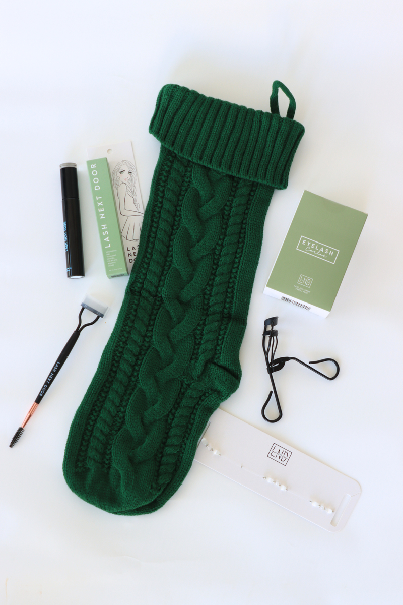 Green knitted sock with knitting tools and materials on a white background