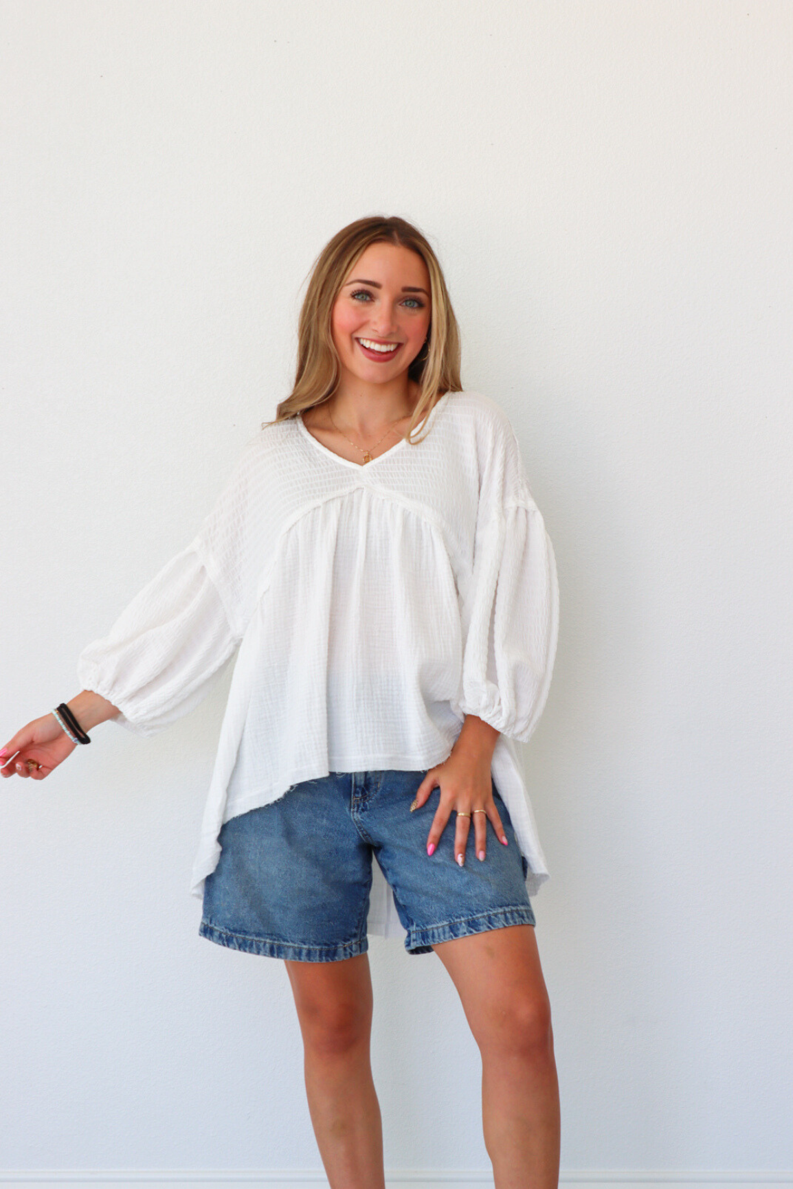 Woman wearing a white blouse and denim shorts against a white background