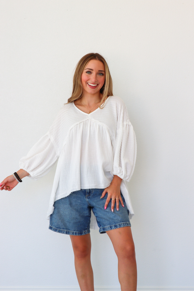 Woman wearing a white blouse and denim shorts against a white background