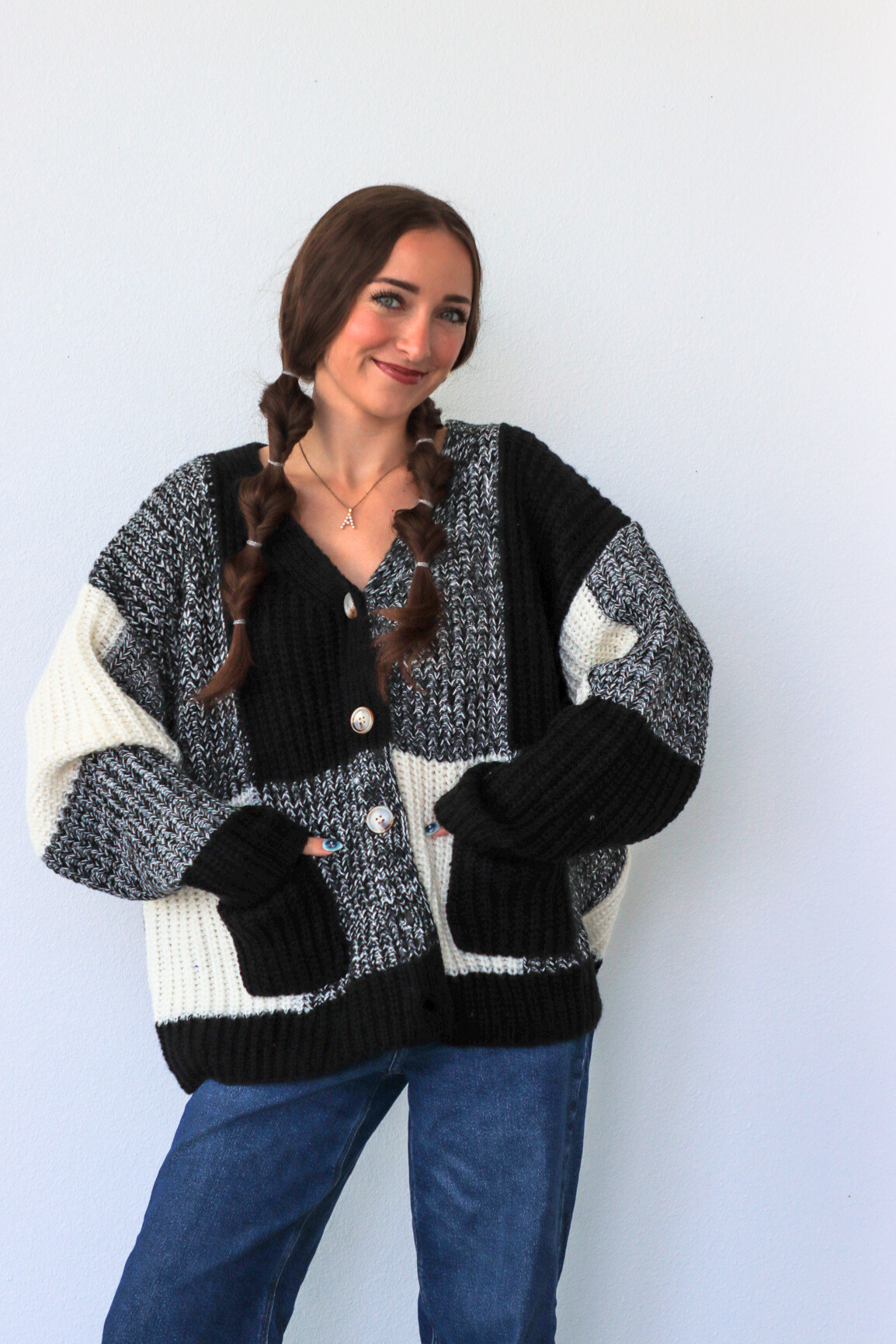 Woman wearing a black and white patterned cardigan against a plain background