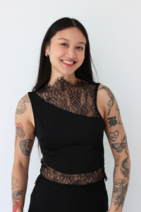 Woman wearing a black lace top against a white background