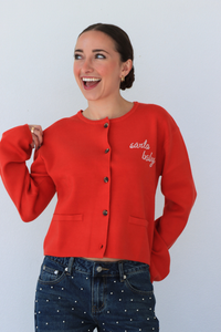 Woman wearing a red cardigan with 'Santa Baby' text against a white background