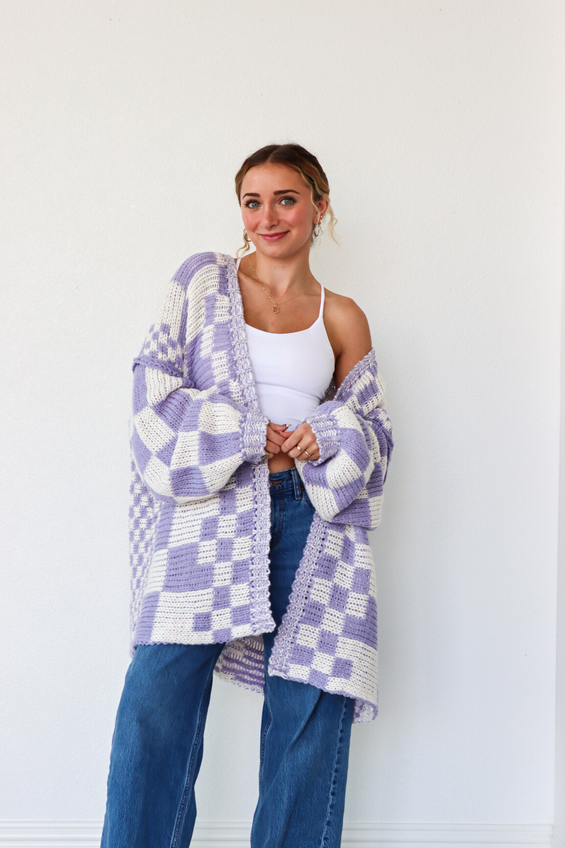 Woman wearing a purple and white checkered cardigan against a white background