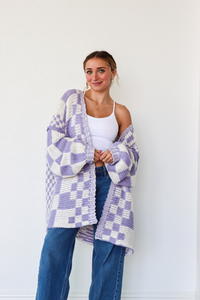 Woman wearing a purple and white checkered cardigan against a white background