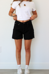 Person wearing a white t-shirt and black shorts against a plain background