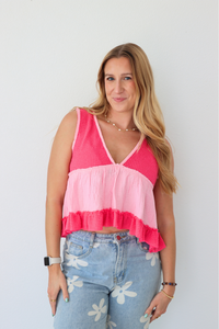 Woman wearing a pink and white top with floral jeans against a plain background