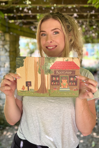 A woman holding a kindle case photographed outdoors under a pergola.