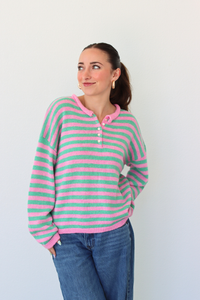 woman wearing a green and pink stripe sweater against a white background
