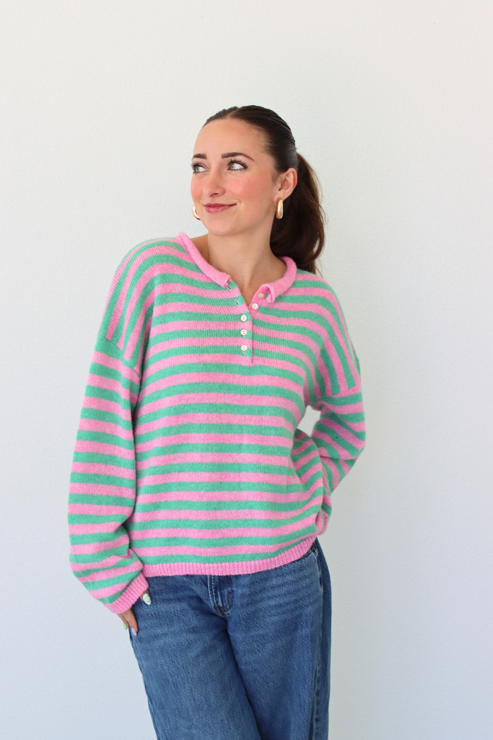 woman wearing a green and pink stripe sweater against a white background